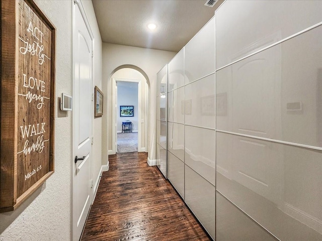 hall with arched walkways and dark wood-type flooring