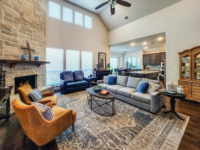 living area with visible vents, a stone fireplace, dark wood finished floors, and a wealth of natural light