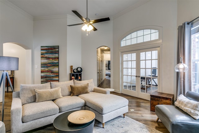 living area featuring arched walkways, french doors, crown molding, and wood finished floors