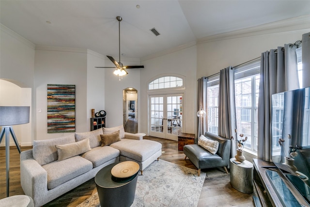 living room featuring arched walkways, french doors, wood finished floors, and ornamental molding