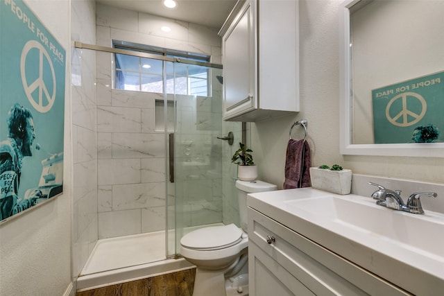 bathroom featuring wood finished floors, a stall shower, vanity, and toilet