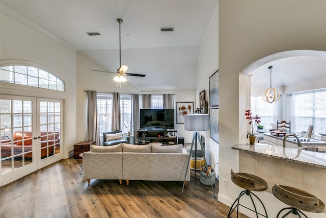 living room featuring crown molding, visible vents, wood finished floors, and ceiling fan with notable chandelier