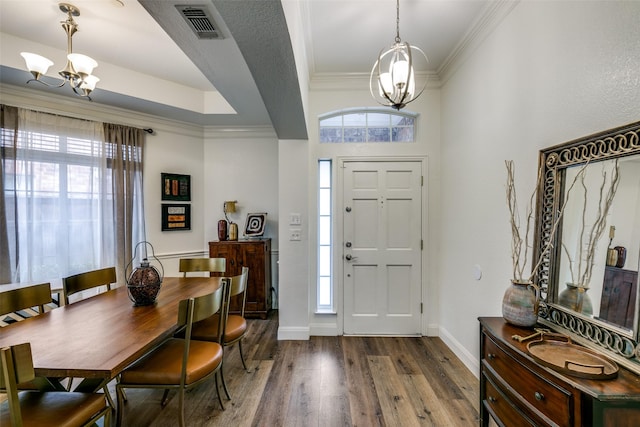 entrance foyer with a wealth of natural light, wood finished floors, crown molding, and an inviting chandelier