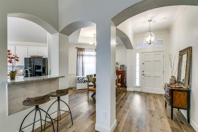 entryway with ornamental molding, baseboards, and wood finished floors