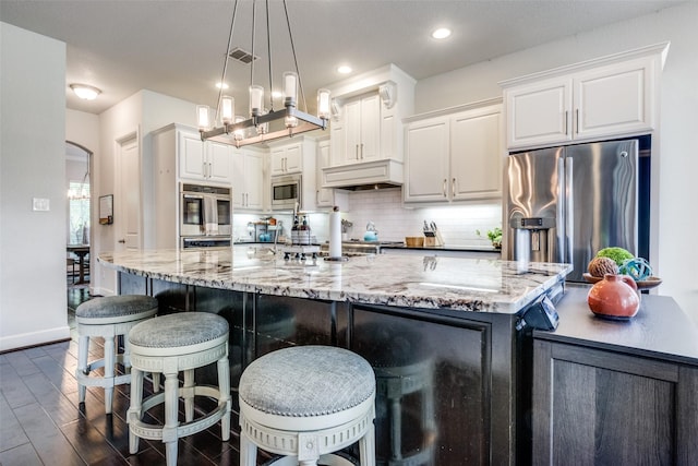 kitchen with tasteful backsplash, stainless steel appliances, custom range hood, white cabinetry, and visible vents