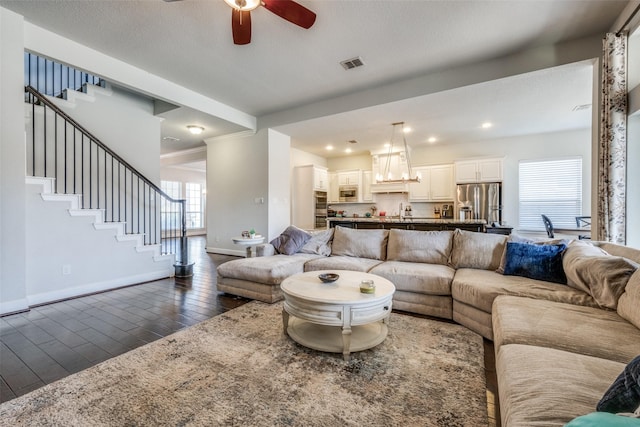 living room featuring a healthy amount of sunlight, dark wood finished floors, visible vents, and stairs