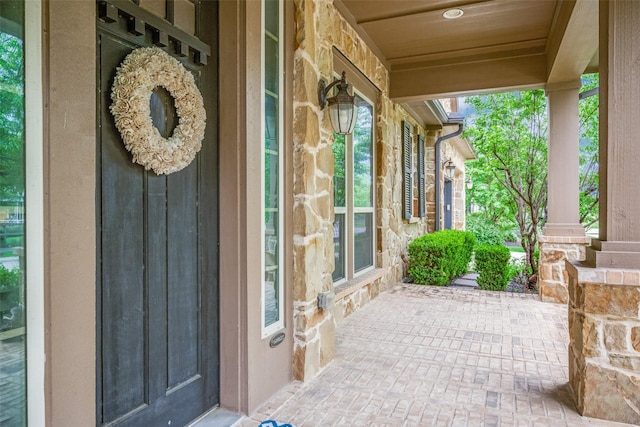 property entrance with covered porch and stone siding
