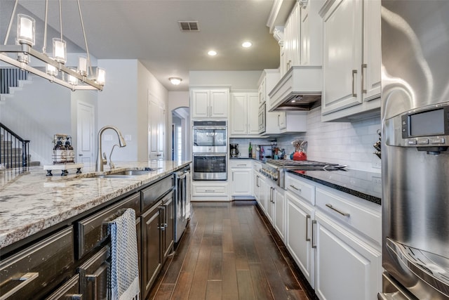 kitchen with stainless steel appliances, white cabinets, a sink, and light stone countertops