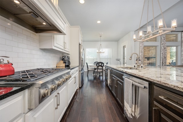 kitchen with stainless steel appliances, white cabinets, premium range hood, and a sink