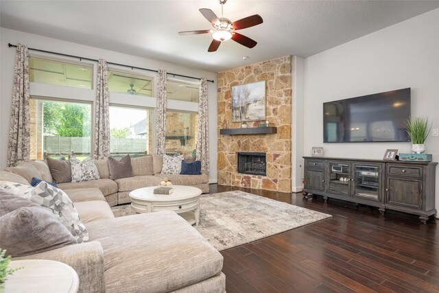 living area with a stone fireplace, hardwood / wood-style flooring, and ceiling fan with notable chandelier