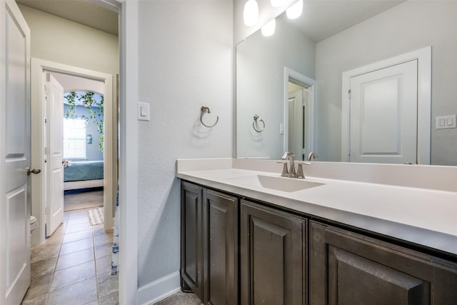 bathroom with tile patterned flooring, baseboards, ensuite bathroom, and vanity