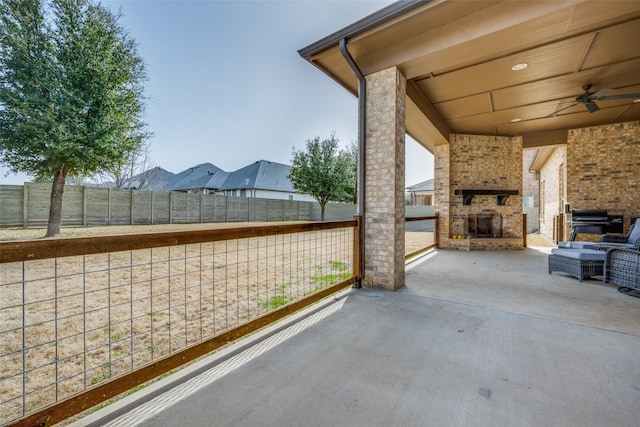 view of patio with an outdoor brick fireplace, fence, ceiling fan, and area for grilling