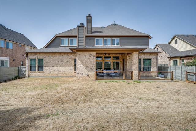 rear view of house featuring a fenced backyard, brick siding, a lawn, a chimney, and a patio area