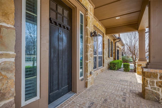 doorway to property featuring stone siding and a porch