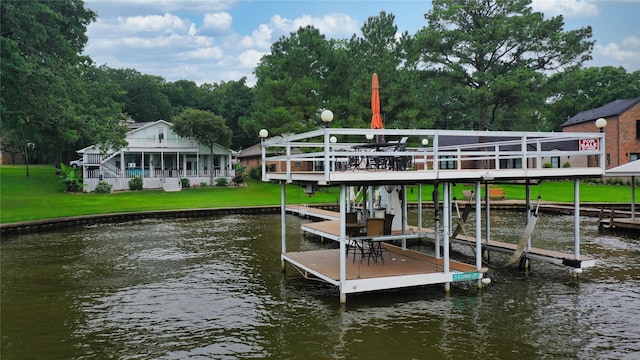 view of dock with a water view, boat lift, and a yard