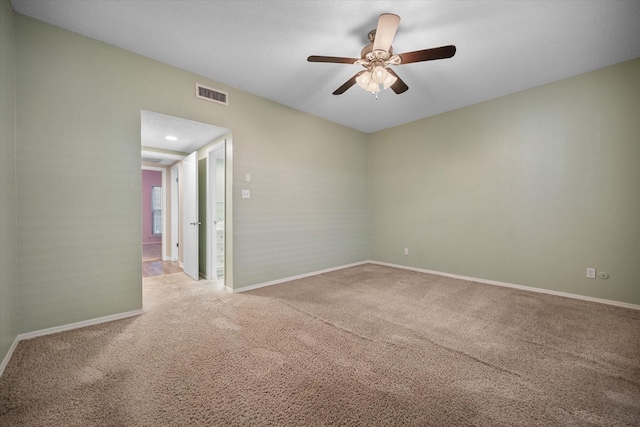 carpeted spare room with visible vents, ceiling fan, and baseboards