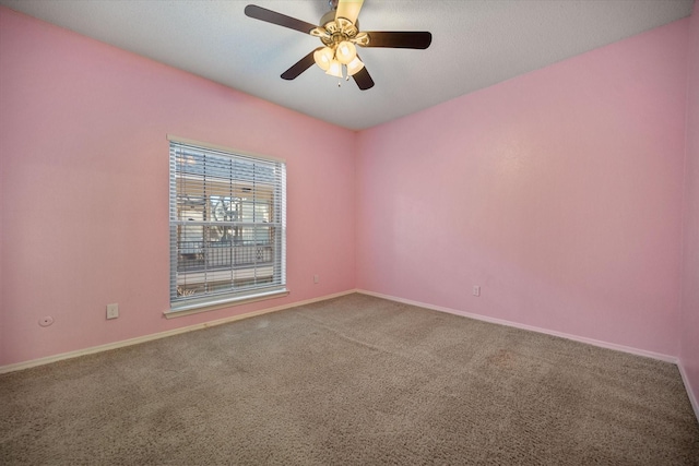 carpeted empty room featuring ceiling fan and baseboards