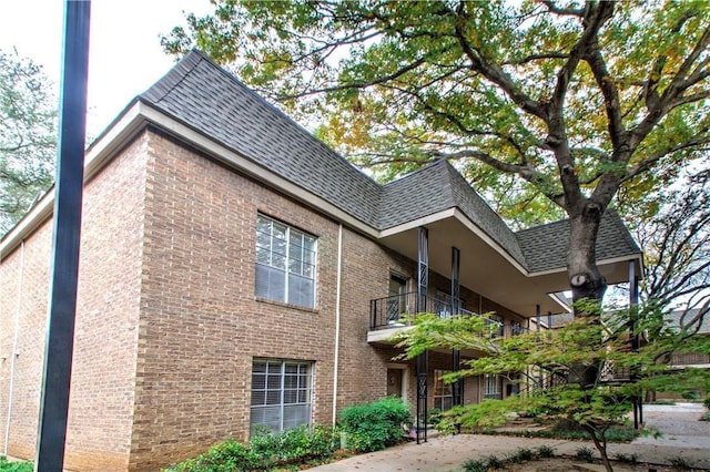 view of property exterior featuring a shingled roof and brick siding