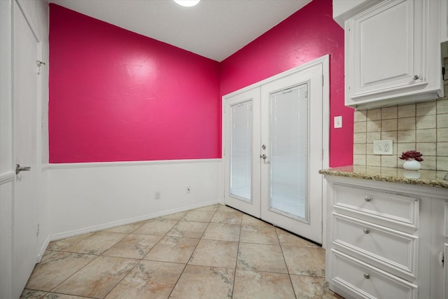 doorway featuring baseboards, light tile patterned flooring, and french doors