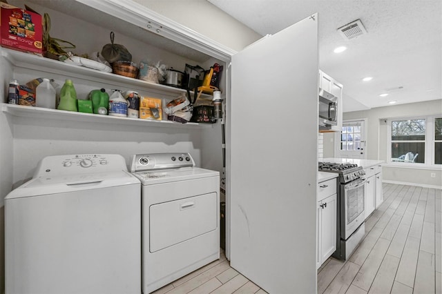 washroom with wood finish floors, recessed lighting, visible vents, washing machine and dryer, and laundry area