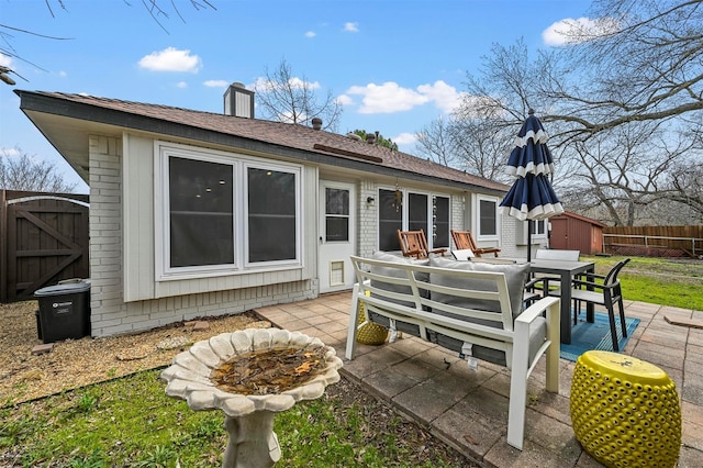 back of property with an outbuilding, fence, a patio area, a shed, and outdoor dining space