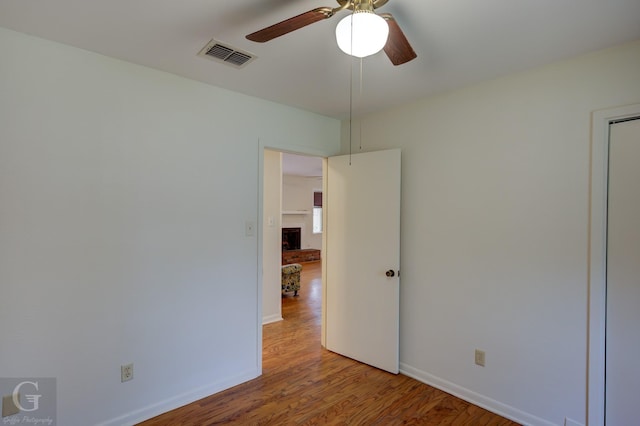 unfurnished room featuring baseboards, wood finished floors, visible vents, and a ceiling fan