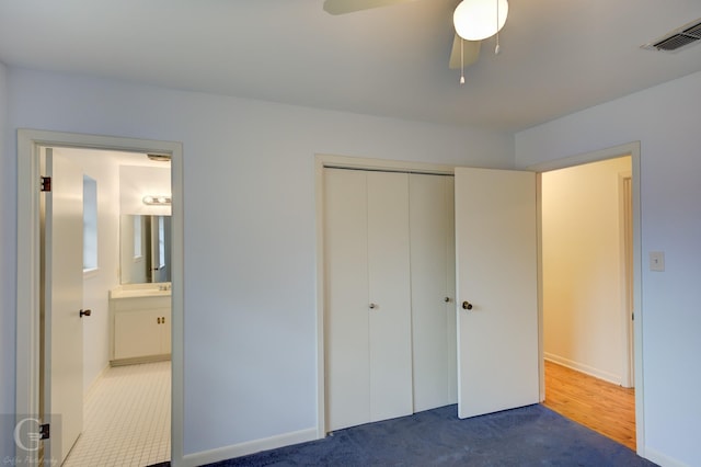 unfurnished bedroom featuring ensuite bathroom, carpet flooring, visible vents, a ceiling fan, and a closet