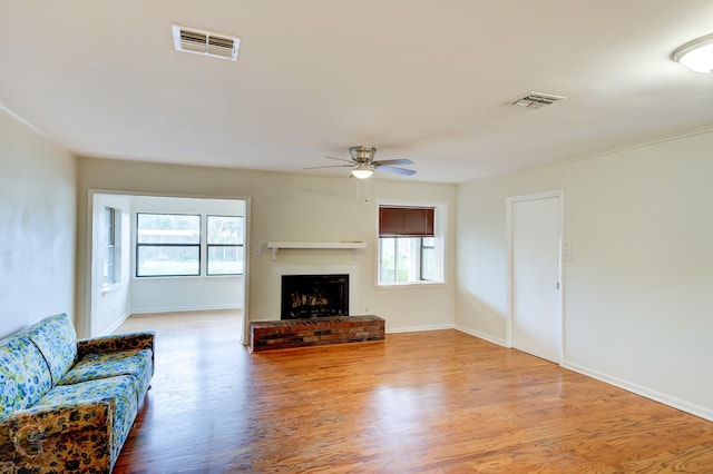 living room with light wood-style floors, a brick fireplace, and visible vents