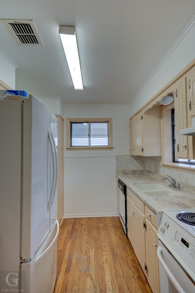 kitchen with white appliances, a sink, visible vents, light countertops, and light wood-type flooring