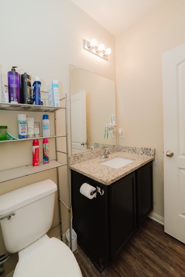 half bath with toilet, wood finished floors, and vanity