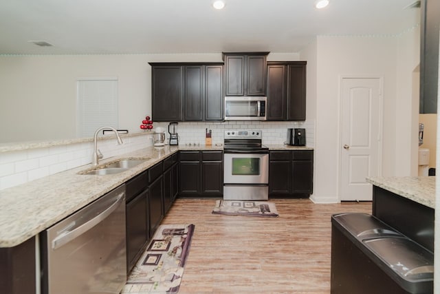 kitchen featuring a sink, visible vents, light wood-style floors, appliances with stainless steel finishes, and decorative backsplash