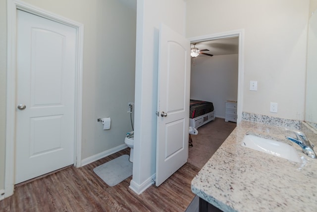 bathroom featuring baseboards, vanity, toilet, and wood finished floors