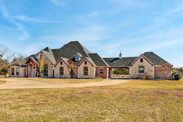 french country inspired facade with concrete driveway and a front yard