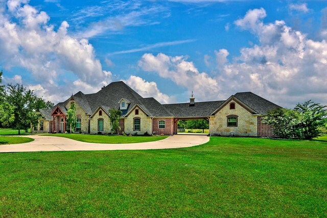 209 Chrissa Dr, Pottsboro, TX 75076 - french country style house featuring curved driveway, a front yard, stone siding, a chimney, and brick siding