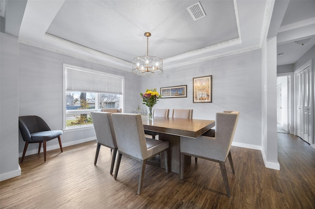 dining space featuring a raised ceiling, visible vents, and wood finished floors