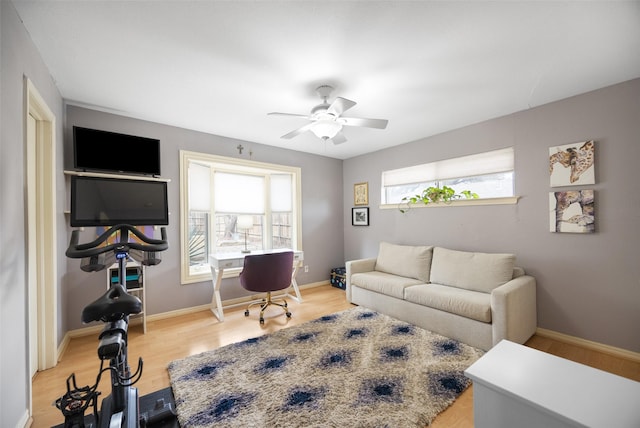 living area with a ceiling fan, baseboards, and wood finished floors