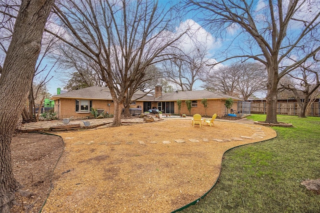 back of property featuring a yard, brick siding, a chimney, and fence