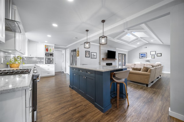 kitchen with dark wood-style floors, appliances with stainless steel finishes, white cabinets, vaulted ceiling with skylight, and extractor fan