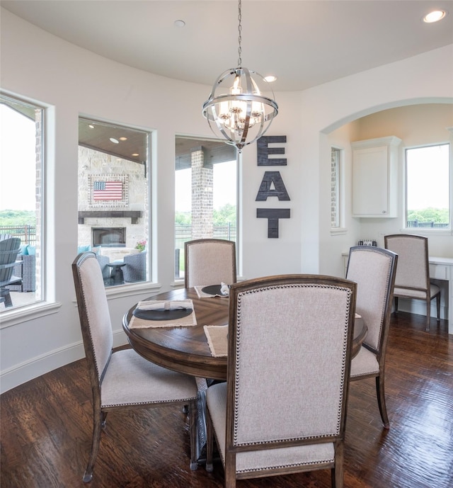 dining room with dark wood-style floors, arched walkways, a notable chandelier, recessed lighting, and baseboards