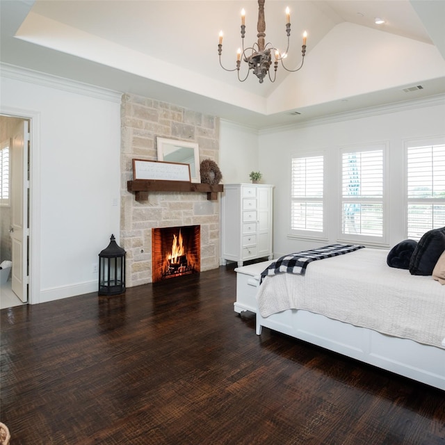 bedroom with wood finished floors, visible vents, a stone fireplace, and multiple windows