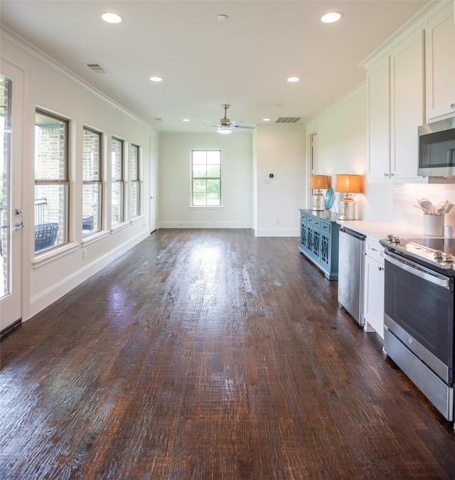 kitchen with visible vents, dark wood finished floors, ornamental molding, stainless steel appliances, and white cabinetry