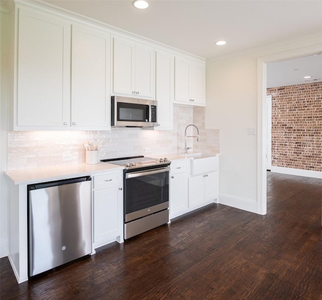 kitchen with stainless steel appliances, a sink, white cabinets, light countertops, and dark wood finished floors