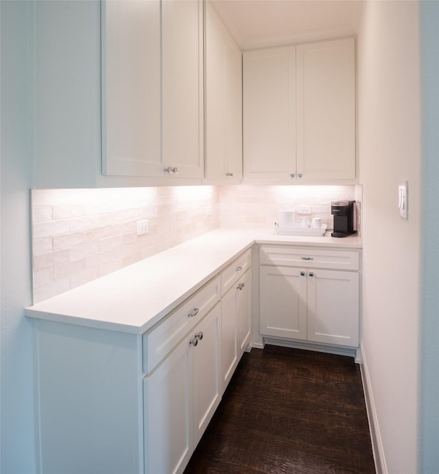 kitchen featuring tasteful backsplash, light countertops, white cabinetry, and dark wood finished floors