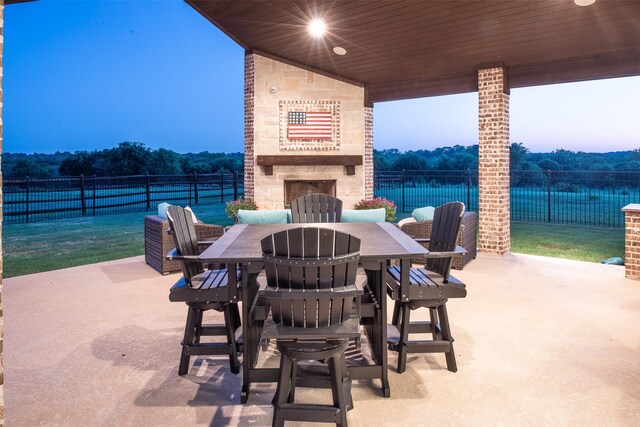 view of patio / terrace with a large fireplace, outdoor dining space, and fence