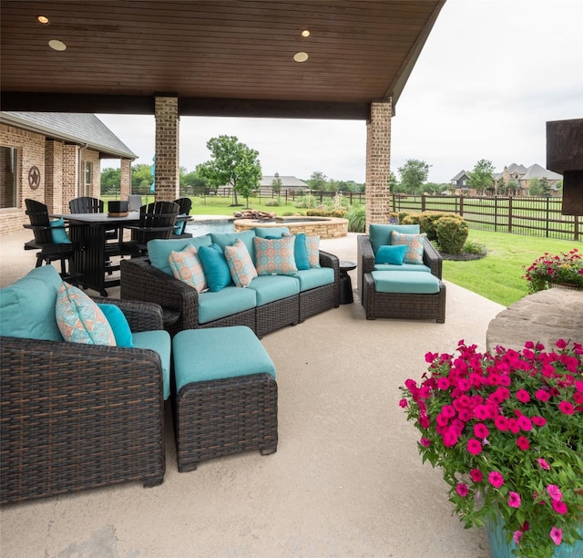 view of patio / terrace featuring an outdoor hangout area, an in ground hot tub, outdoor dining space, and a fenced backyard