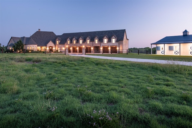 back of house at dusk with a yard and fence