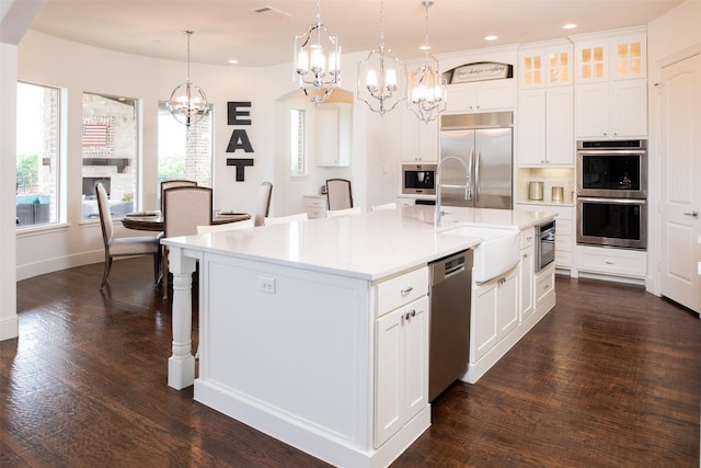 kitchen featuring light countertops, appliances with stainless steel finishes, dark wood-style flooring, and hanging light fixtures