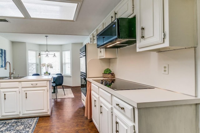 kitchen featuring visible vents, white cabinets, dark wood-type flooring, black appliances, and a sink