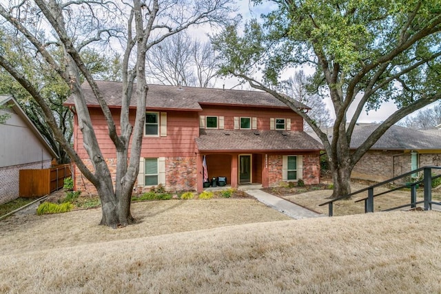 view of front of home featuring a shingled roof, fence, and brick siding