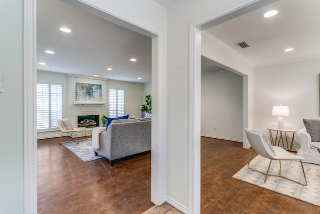 corridor with ornamental molding, a wealth of natural light, visible vents, and wood finished floors